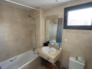 Ein Badezimmer mit Badewanne, Waschbecken, Spiegel und Fenster.