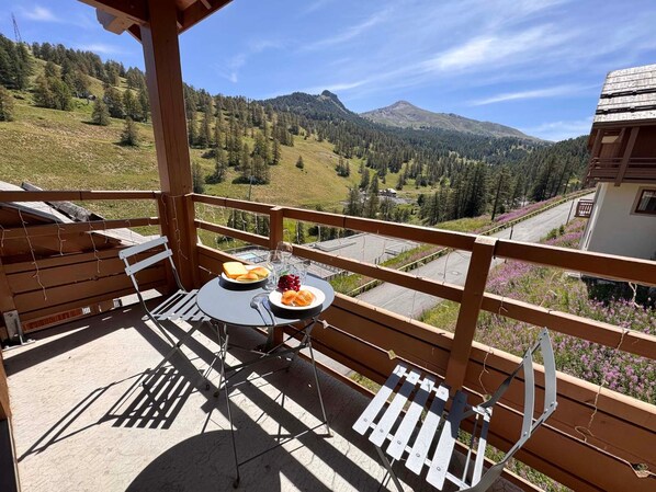 A balcony with a table set for two, overlooking a mountainous landscape. - Apartment mountain view, pets welcome - 6 guests (Vars)