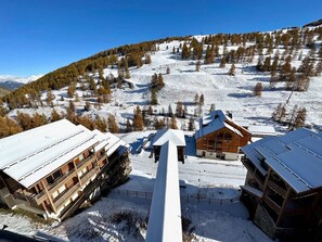 Ein mit Schnee bedeckter Berg mit einem Holzhaus, das mehrere Balkone und eine Seilbahn im Vordergrund zeigt.