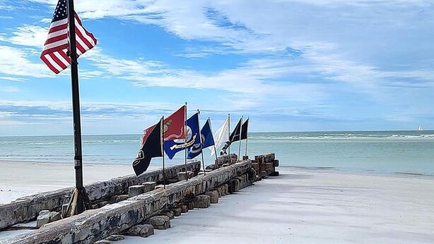 A pier with flags, including the American flag, extending into the water. - Walk to Siesta Key Beach and Village - Beautifully Renovated 2BR Condo (Siesta Key)