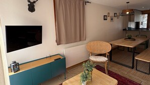 Una sala de estar moderna con televisor, cabeza de venado montada, comedor y ventana con cortinas.
