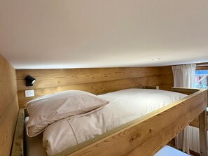 Ein Stockbett mit Holz-Kopfteil, einer Wandleuchte und einer Steckdose.