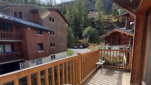 Un balcón de madera con vista a una montaña y un edificio.