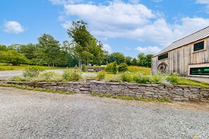 A rustic building with a stone wall and a large tree in the background.
