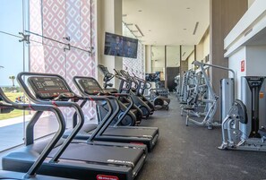 A gym with treadmills, weight machines, and a TV screen. - Enjoy this new luxurious ground floor 3 bed condo in the heart of Rocky Point! (Puerto Peñasco)