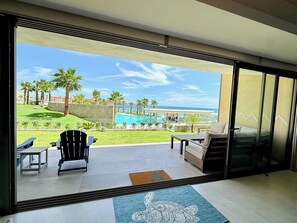 Ein Zimmer mit Blick auf einen Pool, Palmen und einen Strand.