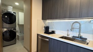 Moderni keittiö, jossa on tummat puukalusteet, ruostumattomasta teräksestä valmistettu allas ja astianpesukone.