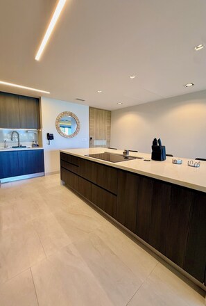 A modern kitchen with a central island, a built-in sink, and a round mirror on the wall. - Enjoy this new luxurious ground floor 3 bed condo in the heart of Rocky Point! (Puerto Peñasco)