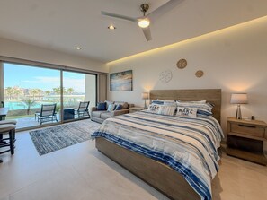 Ein modernes Schlafzimmer mit einem großen Bett, einem Deckenventilator und Blick auf einen Swimmingpool.