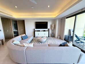 Ein modernes Wohnzimmer mit einer gebogenen Couch, einem Couchtisch und einem Flachbildfernseher.