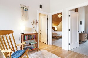 A cozy room with a wooden chair, a bookshelf, a white rug, and a bed in the background. - Ski Bunny Betsy's Chalet | Family  and  Pet-Friendly Mountain Retreat  | Hot Tub | Mountain Views | 5 Minutes to the Lifts (Mount Washington)