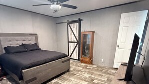 A bedroom with a bed, a ceiling fan, a wooden cabinet, and a door. - Countryside Home (Rayville)