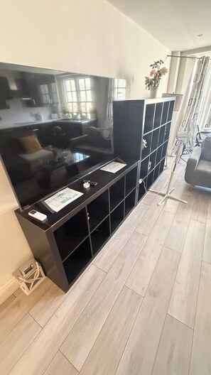 Ein modernes Wohnzimmer mit großem Flachbildfernseher, integrierten Regalen und einem grauen Sofa.