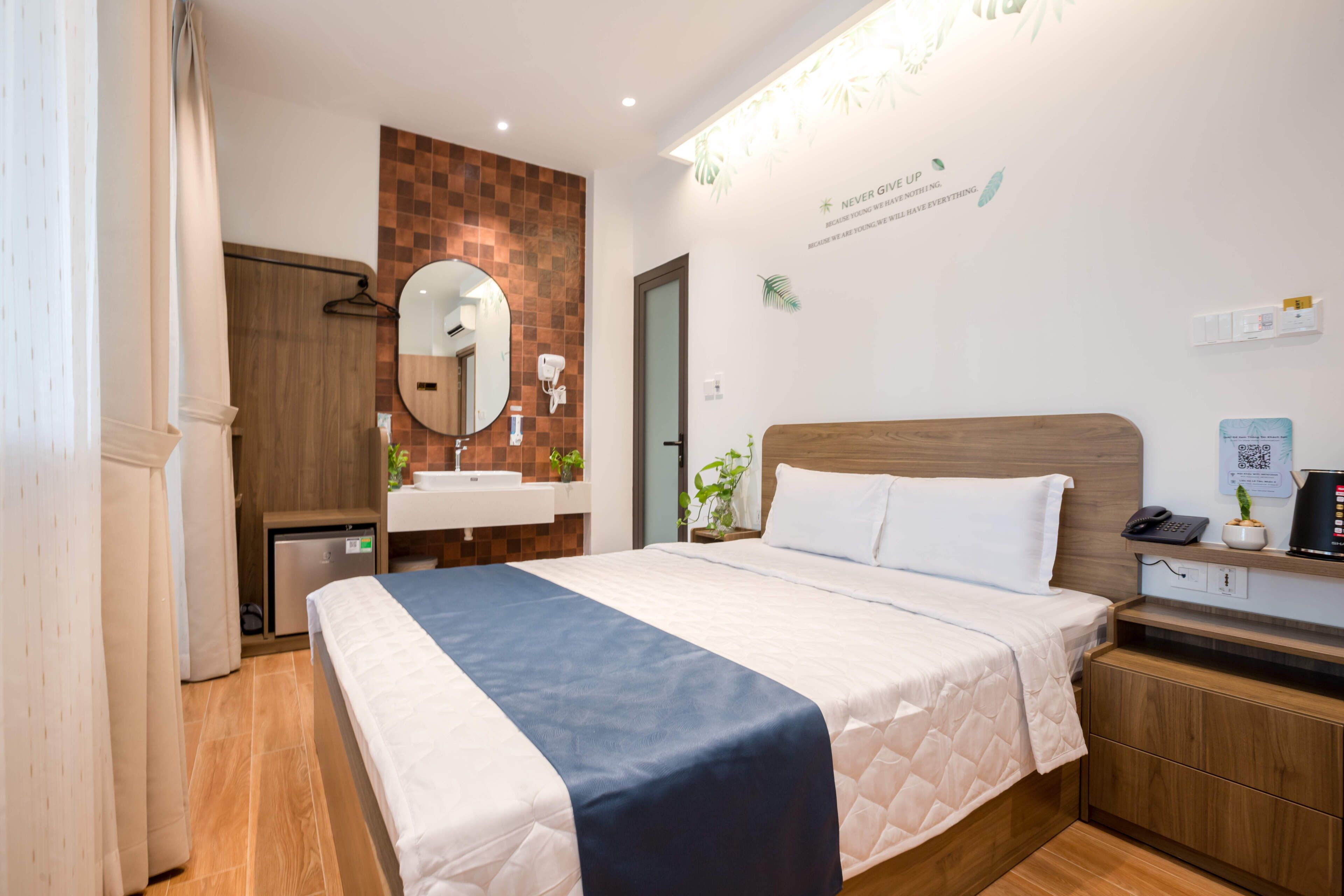 Une chambre d'hôtel équipée d'un lit, d'une table de chevet, d'un miroir et d'une étagère murale où sont disposés des articles de toilette.