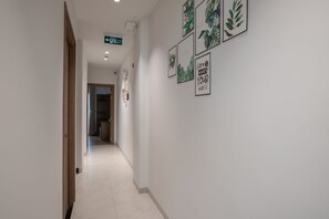 Un pasillo con un letrero que indica una salida, impresiones botánicas enmarcadas en la pared y un piso de baldosas limpias.