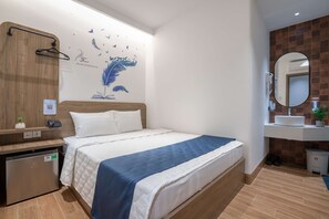 A hotel room with a bed, a bedside table, a mirror, and a wall with a bird and nature mural.