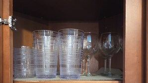 Une étagère en bois sur laquelle sont empilés des verres transparents, et en dessous, un appareil électroménager noir.