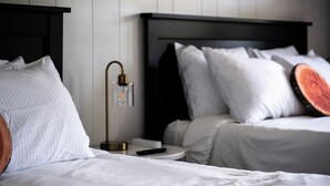 A hotel room with two beds, a nightstand, a lamp, and a remote control. - Lumber Jill Lodge Rooms (Balsam Lake)