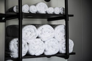A black metal shelf with neatly rolled white towels.