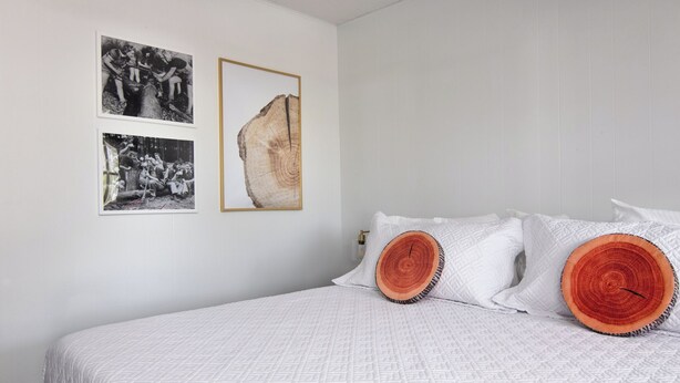 Un dormitorio con una cama, ropa de cama blanca y tres fotografías enmarcadas en la pared.