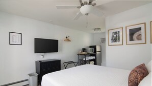A bedroom with a bed, a TV, a ceiling fan, a dresser, and framed pictures on the wall. - Lumber Jill Lodge Rooms (Balsam Lake)