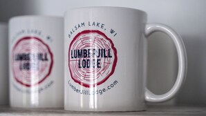 Two white mugs with red and black text, one of which reads 'Lumber Jill Lodge' and the other 'Balsam Lake, WI'. - Lumber Jill Lodge Rooms (Balsam Lake)