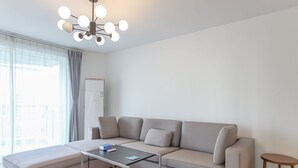 A modern living room with a sofa, ottoman, and a glass coffee table. - Tyms 3BR 2BA Residence Xujiahui (Shanghai)