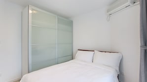 A bedroom with a bed, a wardrobe, and an air conditioning unit. - Tyms 3BR 2BA Residence Xujiahui (Shanghai)