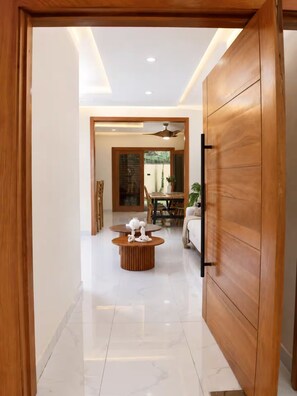 A modern interior with a wooden door, a dining area with a table and chairs, and a white sofa.