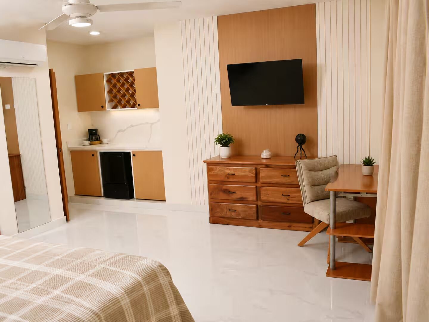 Une chambre moderne comprenant un lit, un bureau avec une chaise, une télévision et un coin cuisine.