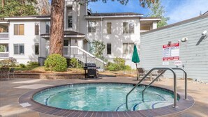 A swimming pool with a hot tub, surrounded by a patio area with outdoor furniture. - Mountain View Ski-In/Out Palisades Condo Hot-Tub (Olympic Valley)