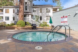 Ein Schwimmbecken mit Whirlpool, umgeben von einer Terrasse mit Gartenmöbeln.