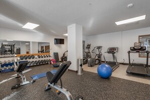 Ein Fitnessstudio mit Laufbändern, Crosstrainern und Kurzhanteln.