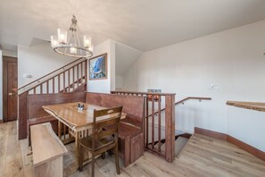 A dining area with a wooden table and chairs, a chandelier, and a staircase with wooden railings. - Donner Lakeview Home for 10 Private Hot-Tub (Truckee)