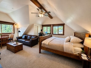 A bedroom with a sloped ceiling, a bed, a desk, a chair, and a couch. - Donner Lakeview Home for 10 Private Hot-Tub (Truckee)