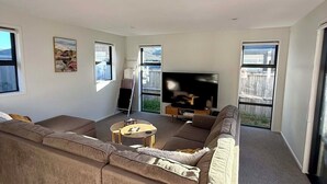Un salon moderne avec un grand canapé d’angle, un téléviseur à écran plat et une petite table basse.