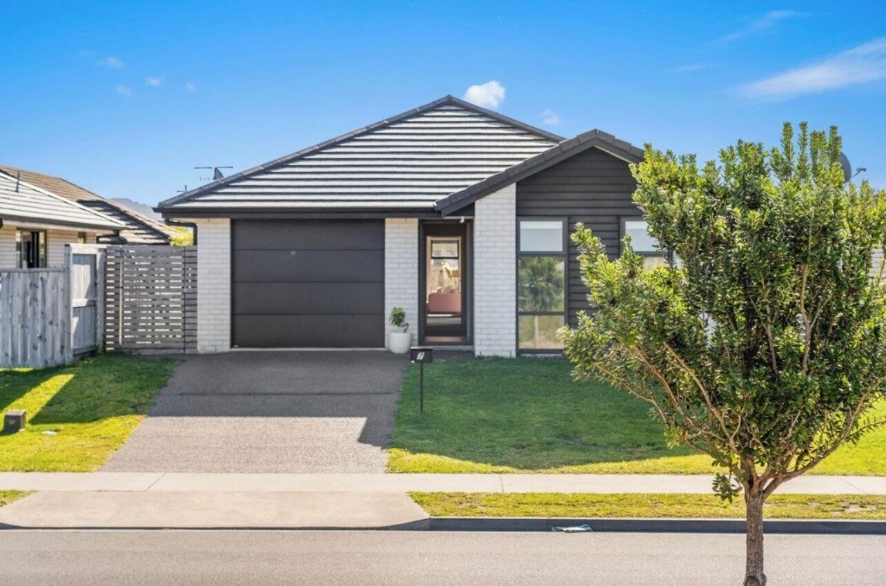 Une maison moderne à deux étages, avec un toit foncé, un garage et une pelouse bien entretenue.