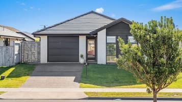 Une maison moderne à deux étages, avec un toit foncé, un garage et une pelouse bien entretenue.