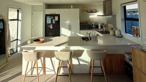 A modern kitchen with a central island, bar stools, and a microwave.