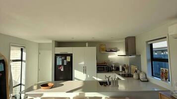 A modern kitchen with a central island, bar stools, and a microwave.