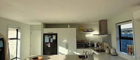 Una cocina moderna con una isla central, taburetes de bar y un microondas.