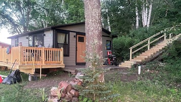 A cabin with a deck, a staircase, and a small garden area.