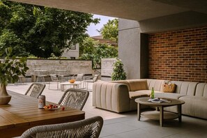 Eine Terrasse mit einer Sitzecke, Tischen und einer Backsteinmauer.