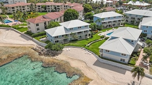 Un complejo turístico frente al mar con villas, aguas turquesas cristalinas y abundante vegetación.