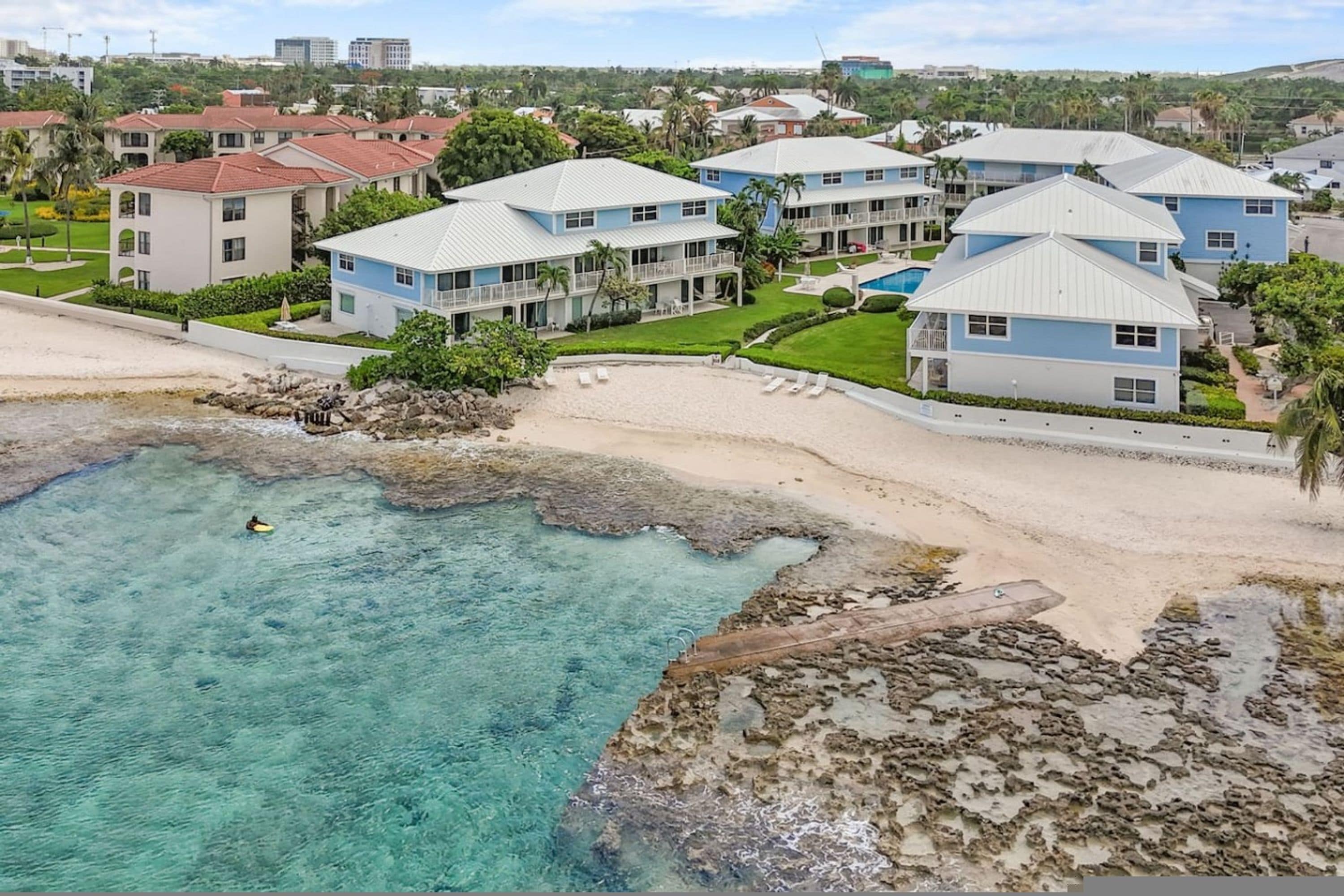 Un hotel costero con varias construcciones, una playa y agua turquesa cristalina.