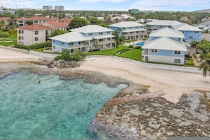 Un hotel costero con varias construcciones, una playa y agua turquesa cristalina.
