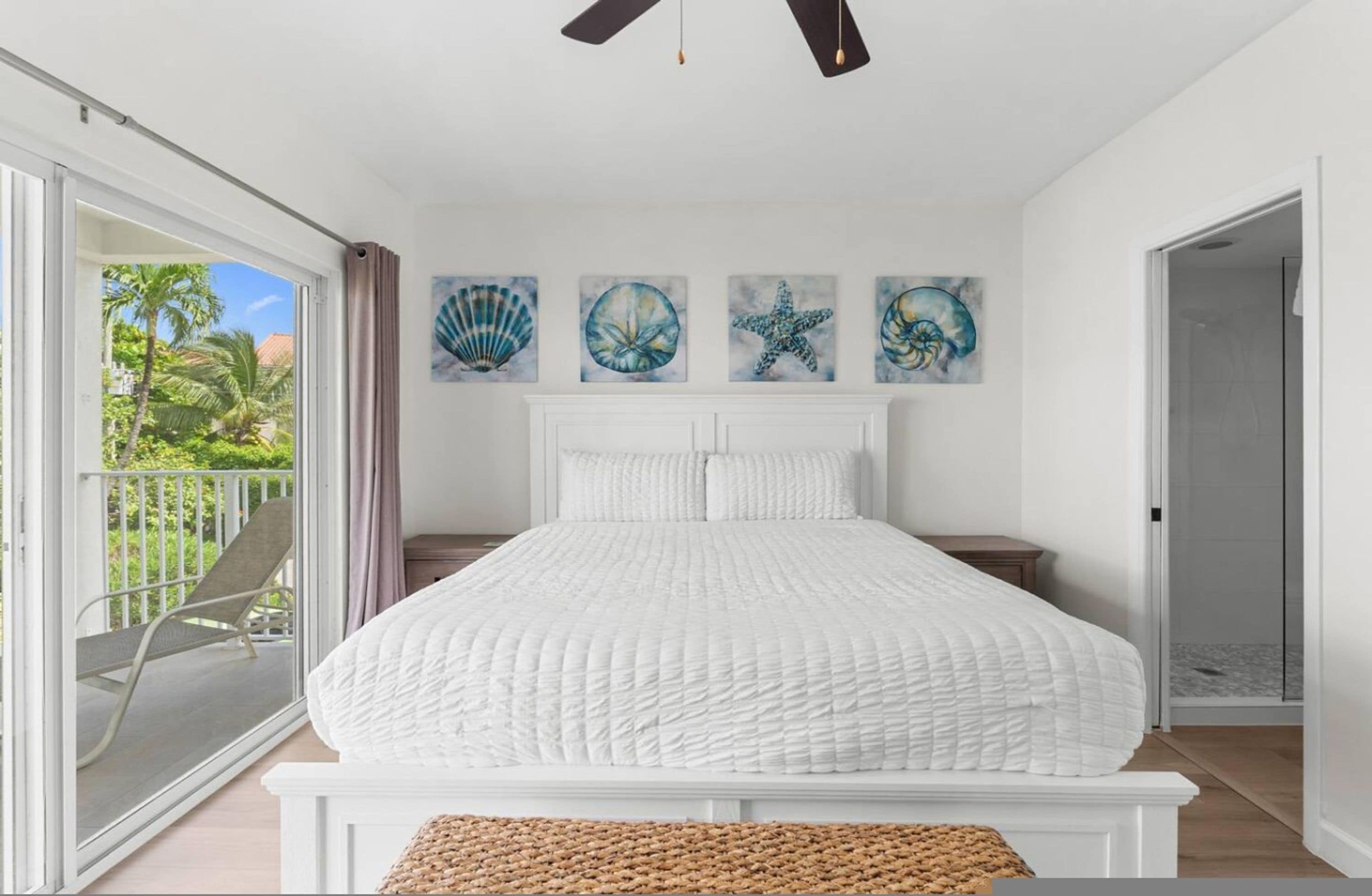 Quarto com uma cama grande, uma varanda com cadeira e três obras de arte na parede.