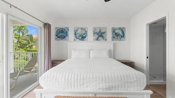 Quarto com uma cama grande, uma varanda com cadeira e três obras de arte na parede.
