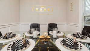 A conference room with a glass table, black and white patterned tableware, and a chandelier.