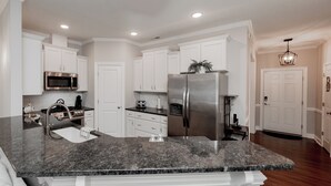 A modern kitchen with white cabinetry, stainless steel appliances, and a granite countertop.